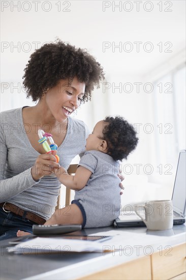 Mother holding toy playing with baby son