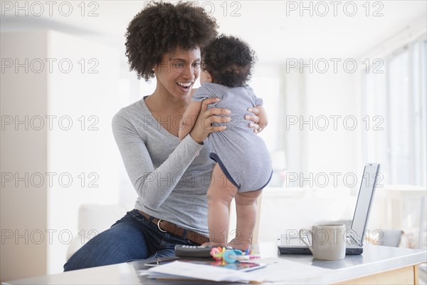 Mother helping baby son stand on counter