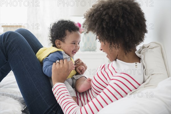 Mother holding baby son in lap on bed