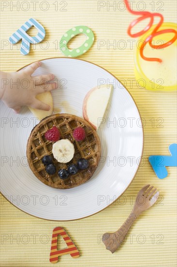 Caucasian baby girl reaching for apple slice