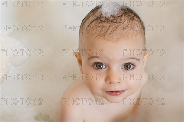 Caucasian baby girl in bathtub with soap in hair