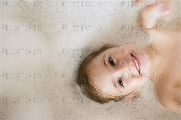 Caucasian girl smiling in bubble bath