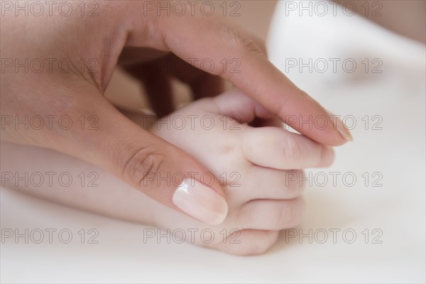 Hand of mother holding hand of baby son