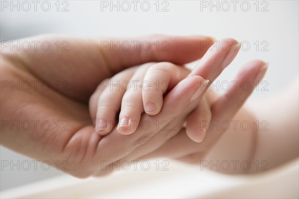 Hand of mother holding hand of baby son