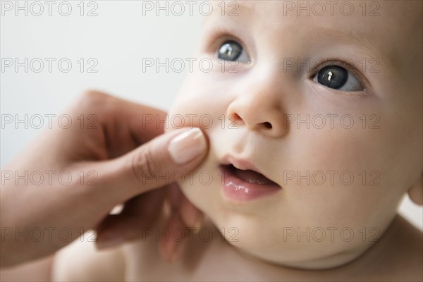 Hand of mother pinching cheek of baby son