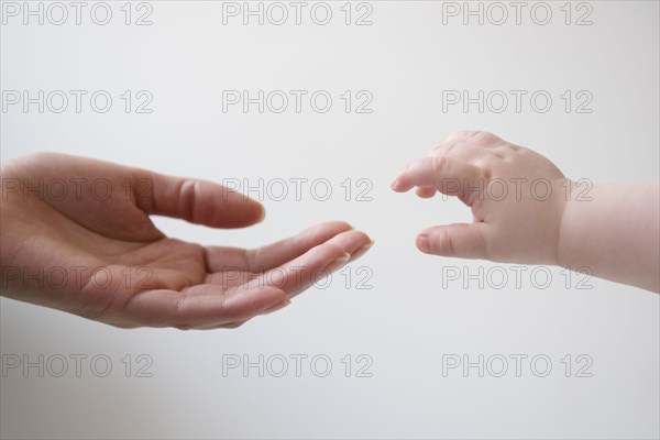 Hand of mother reaching for hand of baby son