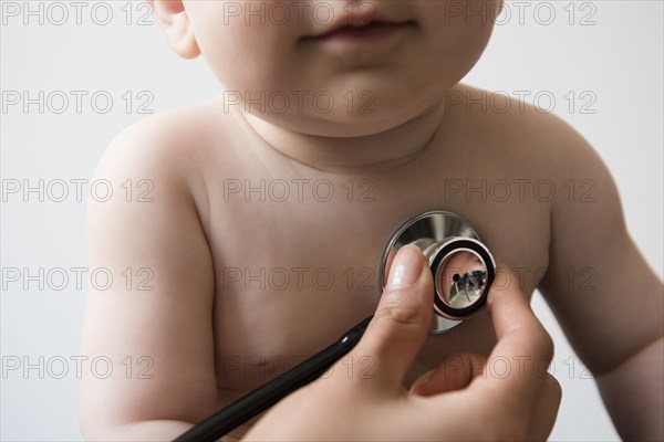 Doctor listening to chest of baby boy with stethoscope