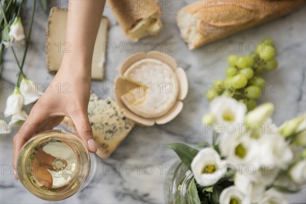 Hispanic woman drinking wine with cheese