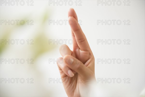 Hand of Hispanic woman with fingers crossed