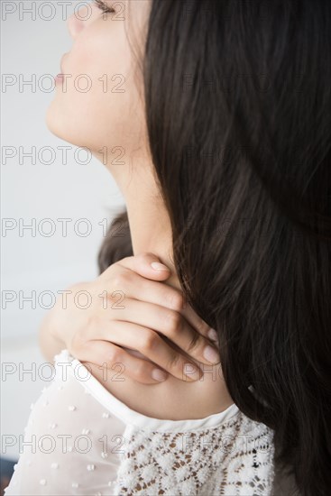 Hispanic woman rubbing shoulder