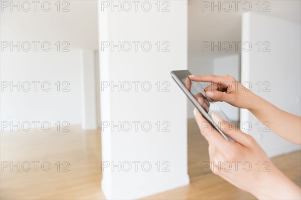 Hands of Hispanic woman using digital tablet in empty apartment