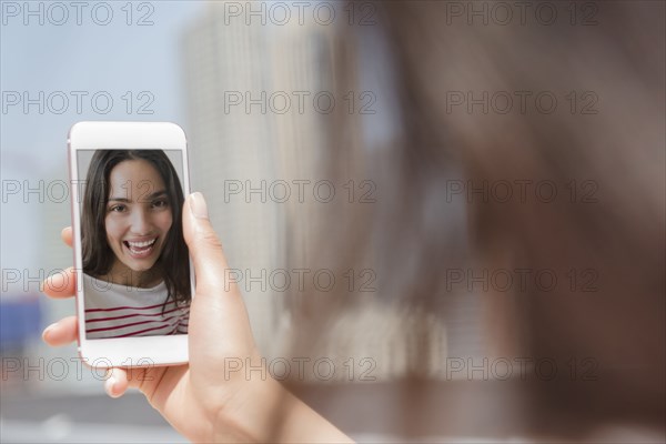 Smiling Hispanic woman posing for cell phone selfie