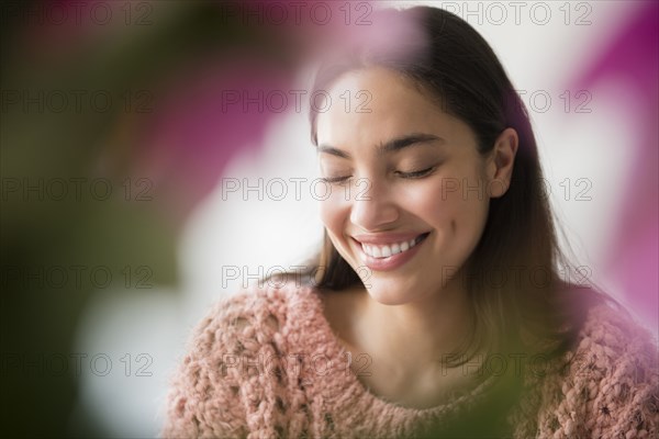 Hispanic woman smiling behind pink flowers