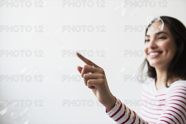 Hispanic woman popping floating bubbles