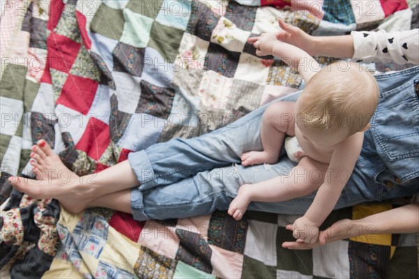 Caucasian mother sitting on blanket with baby son on lap