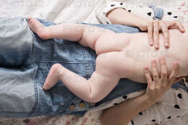 Caucasian mother laying on bed holding naked baby son