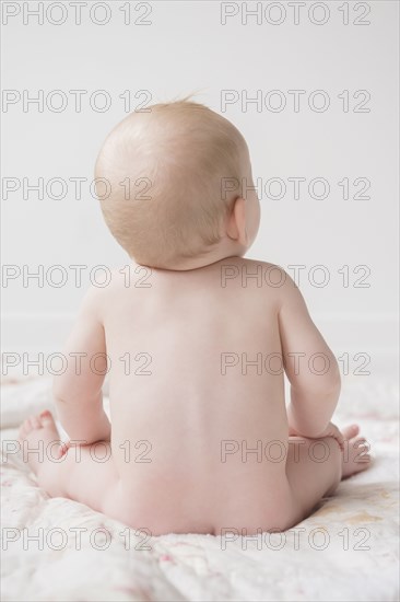 Naked Caucasian baby boy sitting on blanket