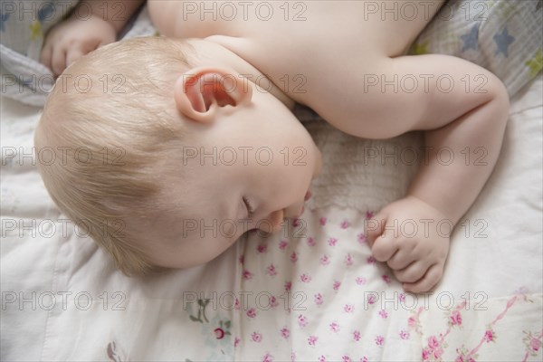 Caucasian baby boy sleeping on blanket
