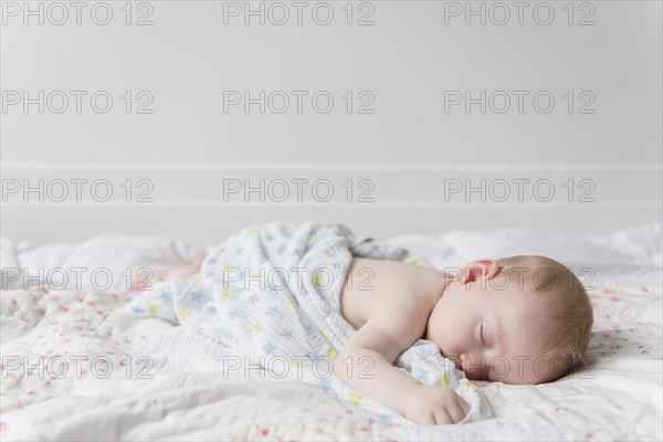 Caucasian baby boy sleeping on bed