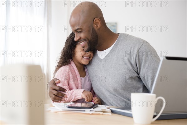 Father hugging daughter at table