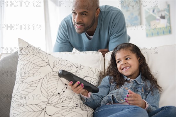 Father and daughter watching television on sofa