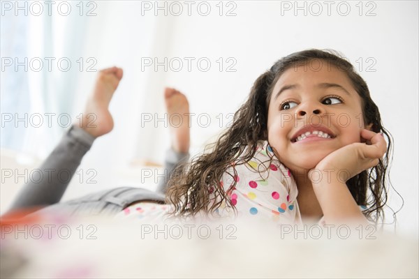 Smiling Mixed Race girl laying on bed