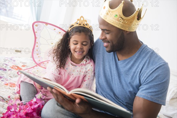 Father ready story to daughter on bed