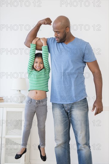 Father lifting daughter using biceps