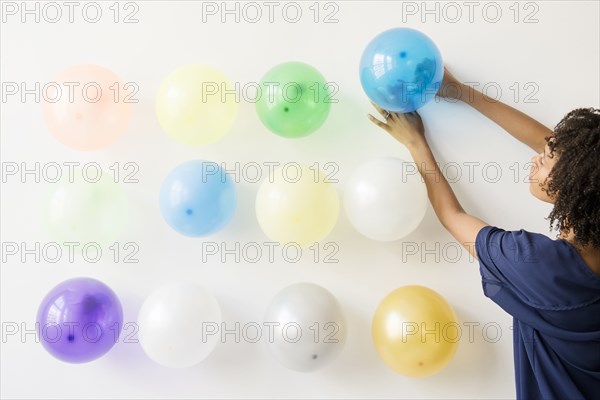 Black woman attaching balloons to wall