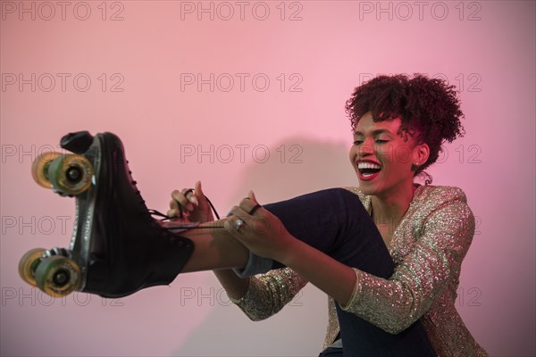 Glamorous Black woman tying roller skate