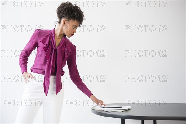 Black woman wearing purple blouse checking digital tablet