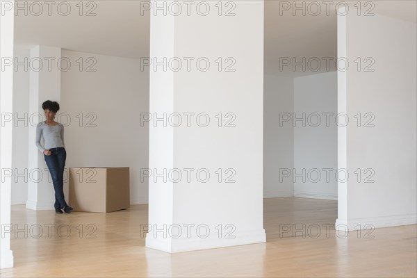 Black woman leaning on pillar in empty apartment