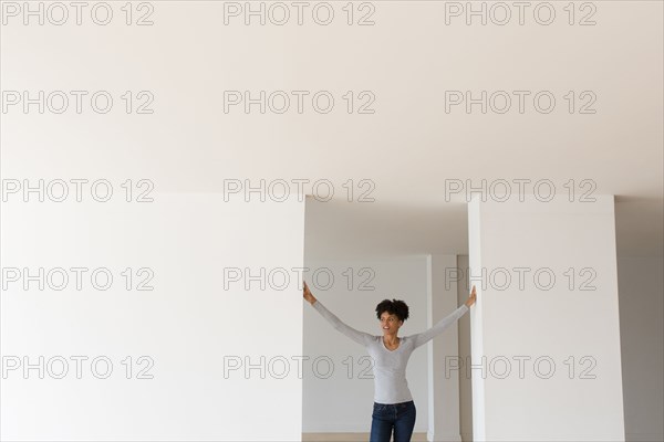 Black woman leaning in doorway in empty apartment