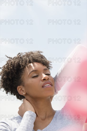 Black woman rubbing neck outdoors