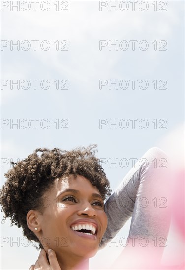 Smiling Black woman rubbing neck outdoors