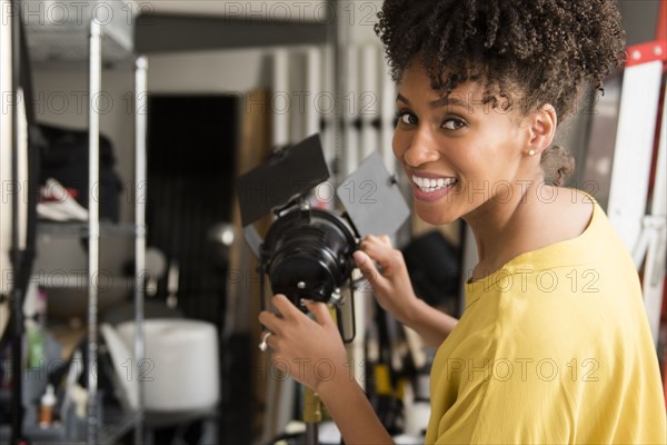 Black photographer adjusting lamp in studio