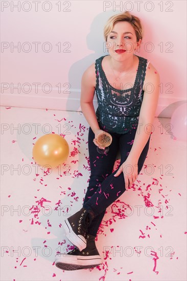 Caucasian woman sitting on floor at party covered in confetti