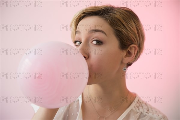 Caucasian woman inflating pink balloon