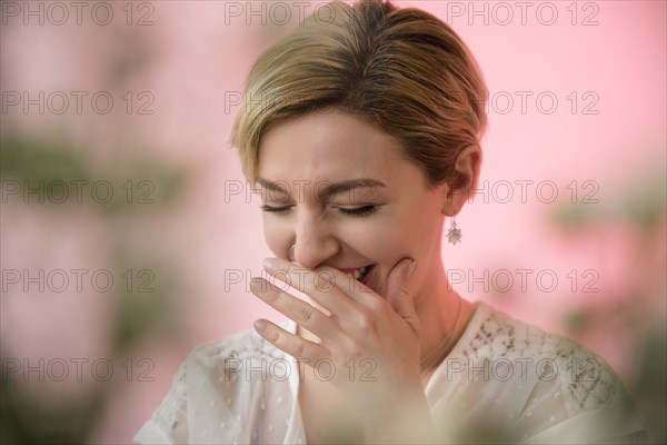 Caucasian woman covering mouth while laughing