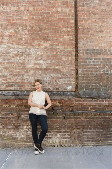 Caucasian woman leaning on brick wall