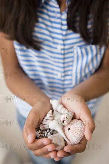 Mixed Race girl holding handful of seashells