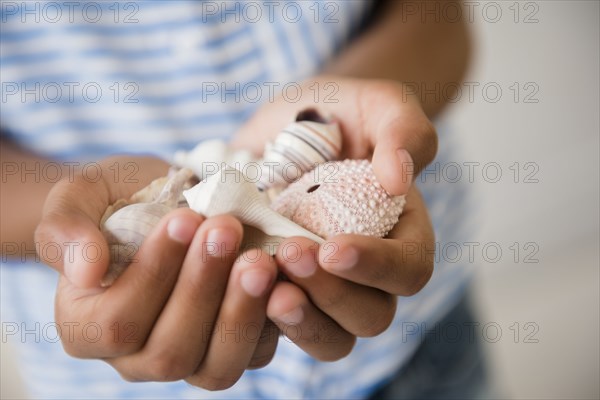 Mixed Race girl holding handful of seashells