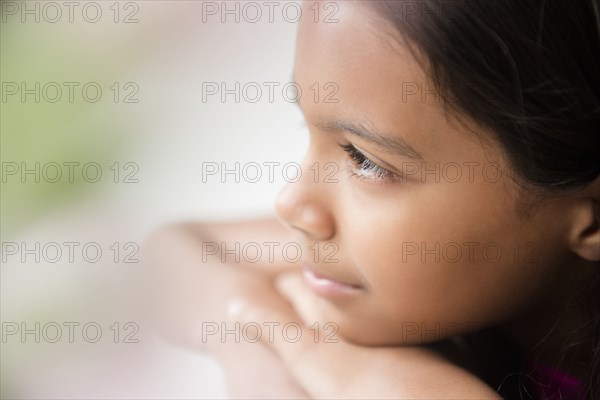 Pensive Mixed Race girl resting chin on hand