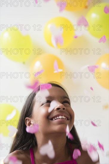 Mixed Race girl watching heart-shape confetti falling