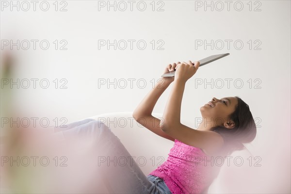 Mixed Race girl relaxing in armchair using digital tablet