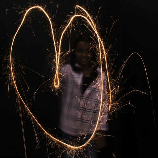 Mixed Race girl making heart-shape with sparkler