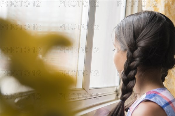 Mixed Race girl looking out window