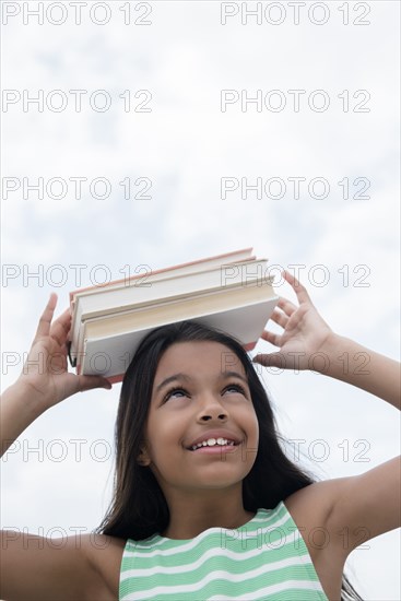 Mixed Race girl balancing books on head