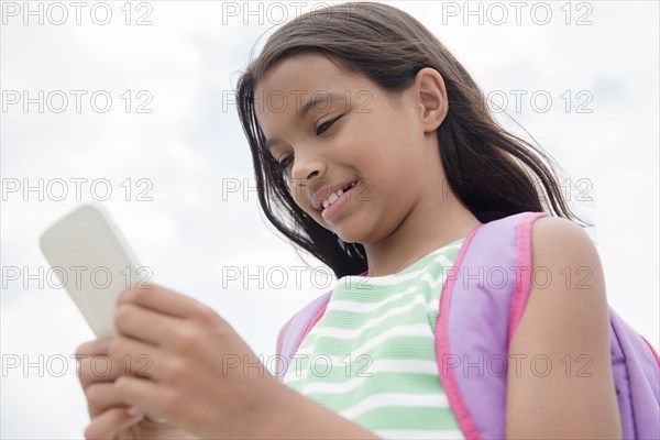 Mixed Race girl carrying backpack texting on cell phone
