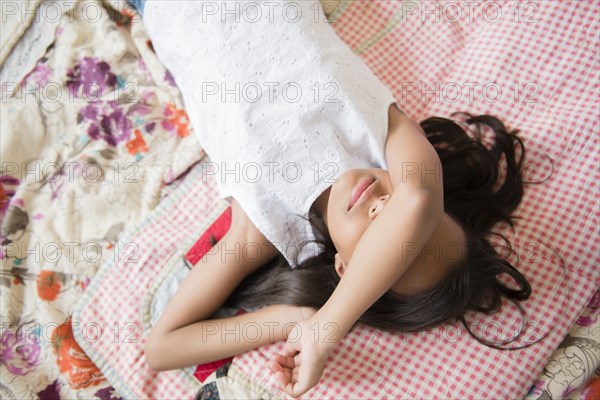 Mixed Race girl laying on bed with arm covering face